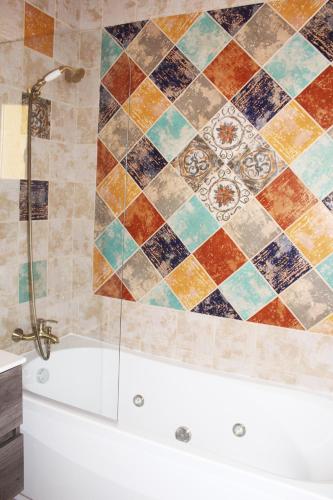 a bathroom with a tub and a tiled wall at Ta' Cikku in Għarb