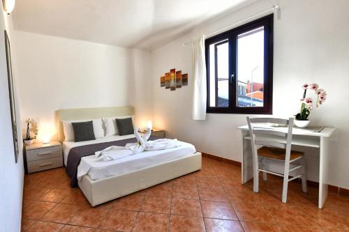 a bedroom with a bed and a desk and a window at Casa Basilia in San Teodoro