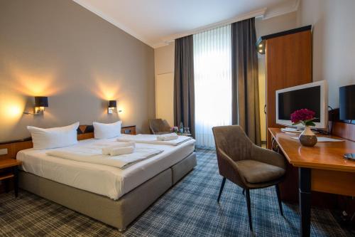 a hotel room with a bed and a desk at Sax Imperial in Dresden