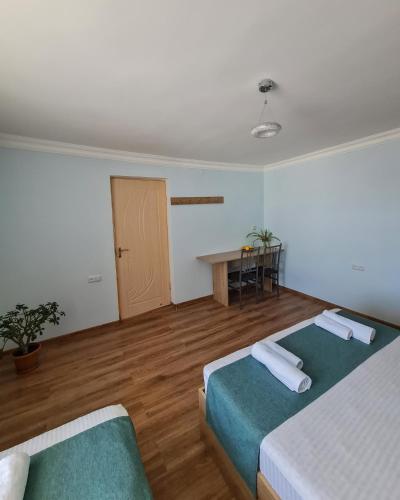 a room with two beds and a table and a door at Seva Guesthouse and Cottages Byurakan in Byurakan