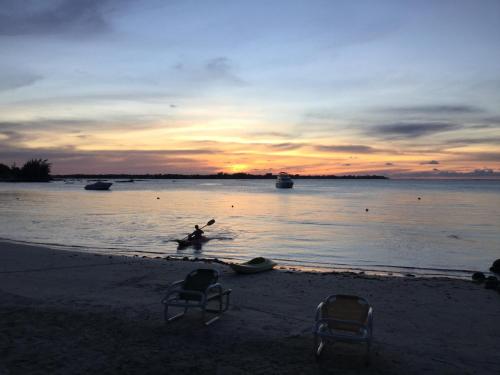 a person standing in the water on the beach at sunset at Fantastic spacious beachfront VILLAVACANCES in Grand Baie