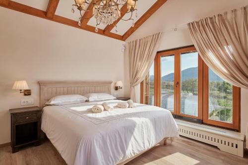 a bedroom with a large white bed with a chandelier at Villa Lovorno in Arbanasi