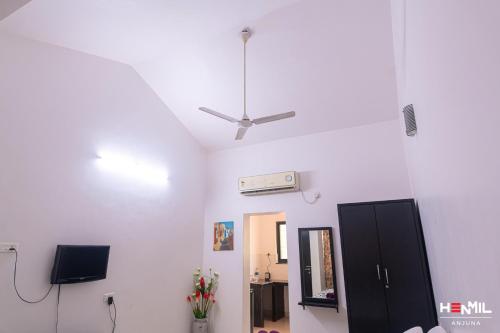 Cette chambre blanche dispose d'un ventilateur de plafond et d'un miroir. dans l'établissement Henmil Anjuna, à Anjuna