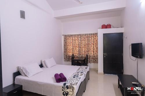 a bedroom with a bed with purple shoes on it at Henmil Anjuna in Anjuna