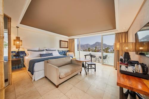 a bedroom with a bed and a couch and a table at Dreams Jardin Tropical Resort & Spa in Adeje