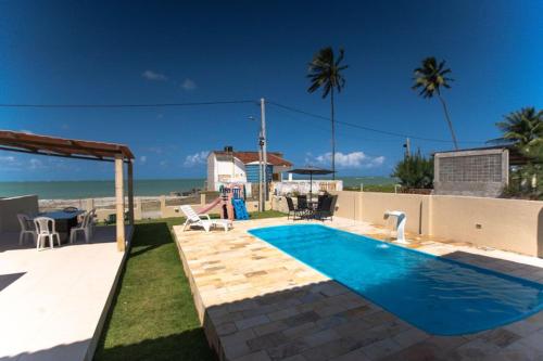 a backyard with a swimming pool and the beach at Casa Beira mar enseada dos golfinhos- Itamaracá in Jaguaribe