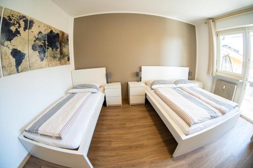 two beds in a room with wooden floors at Flow Apartments Wolkenstein in Merano