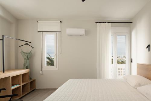 a white bedroom with a bed and two windows at Casa delle Palme in Rethymno Town