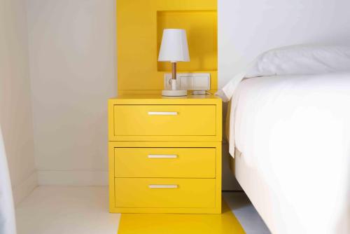a yellow dresser with a lamp on it next to a bed at Hotel Almunia in Caravaca de la Cruz