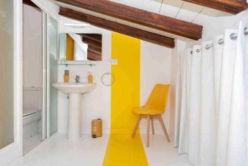a bathroom with a sink and a yellow chair at Hotel Almunia in Caravaca de la Cruz