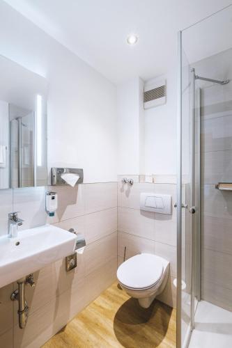 a bathroom with a toilet and a sink and a shower at Dorint Parkhotel Siegen in Siegen