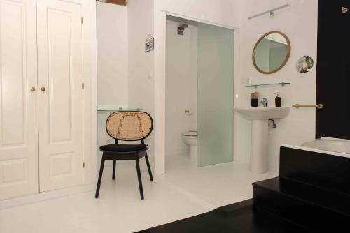 a bathroom with a chair and a sink and a toilet at Hotel Almunia in Caravaca de la Cruz