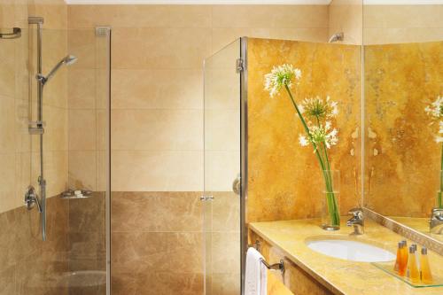 een badkamer met een douche en een wastafel met een vaas met bloemen bij Poli Hotel in San Vittore Olona