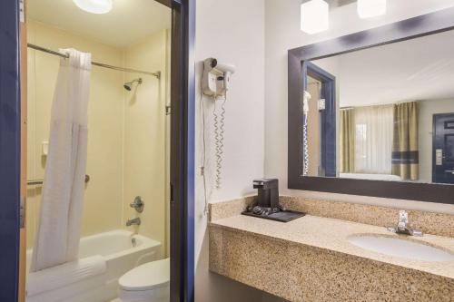 a bathroom with a sink and a toilet and a mirror at Clarion Pointe Forsyth I-75 in Forsyth