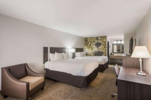 a hotel room with two beds and a chair at Clarion Pointe Forsyth I-75 in Forsyth