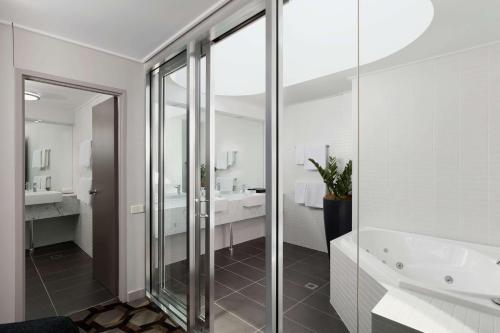 a bathroom with a glass shower and a tub at Rydges Canberra in Canberra