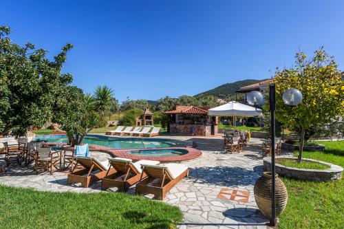a swimming pool with chairs and a table and an umbrella at Ageri Studios in Stafylos
