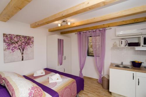 a bedroom with two beds and a kitchen with purple curtains at Lavender Garden Apartments in Dubrovnik