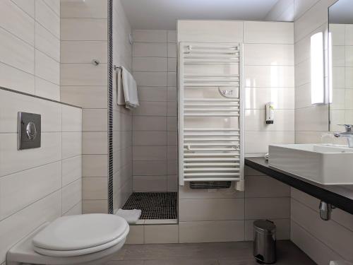 a white bathroom with a toilet and a sink at Hotel Restaurant & Spa Verte Vallée in Munster