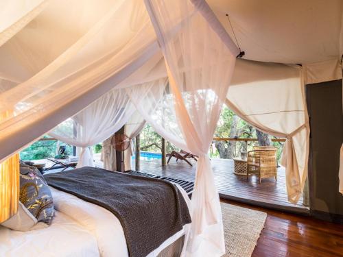 1 dormitorio con cama con dosel y terraza en Rhino Sands Safari Camp, en Manyoni Private Game Reserve