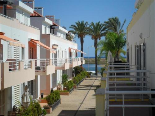 a street in front of buildings with palm trees at Casa da Ria in Cabanas de Tavira