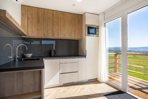 una cocina con armarios de madera y una gran ventana en Royal Village en Malý Slavkov