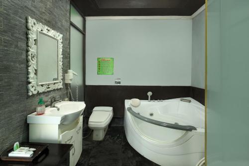 a bathroom with a white tub and a toilet and a sink at Negara Hotel - CHSE Certified in Negara
