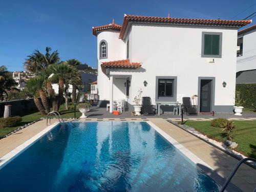 a villa with a swimming pool in front of a house at Funchal Apt- Sleeps 2 - Pool & Garden - Madeira in Funchal