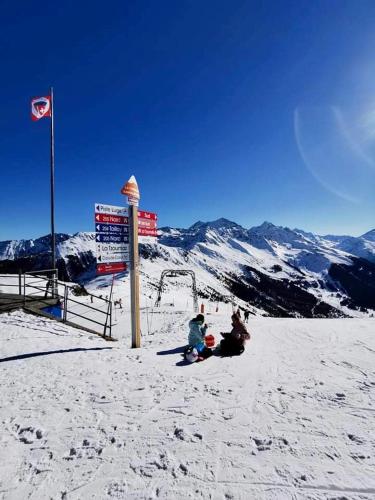 two people sitting in the snow on a ski slope at Studio 4pers aux Bains de Saillon in Saillon