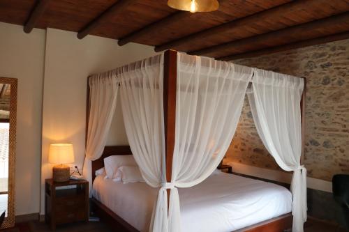 a bedroom with a canopy bed with white curtains at Hotel Palacio Conde del Álamo in Aroche