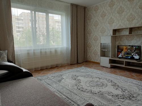 a living room with a television and a large window at Апартаменты на Первомайская 37 "А" in Semey