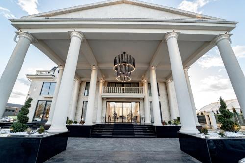 a large white building with columns and a chandelier at Hotel Caprice in Bacău