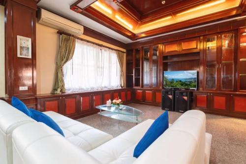 a living room with a white couch and a tv at Angel Pool Villa Phuket - SHA Extra Plus in Phuket Town