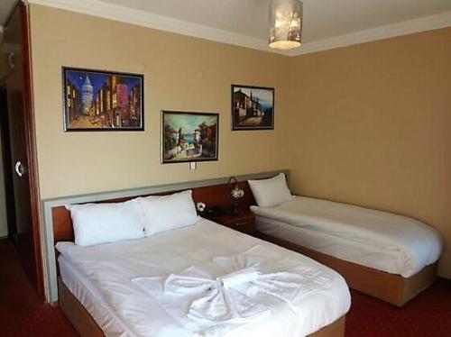 Habitación de hotel con 2 camas y cuadros en la pared en Linda Butik Otel Gümüldür, en Izmir