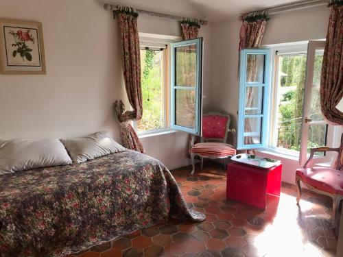 une chambre avec un lit, une chaise et des fenêtres dans l'établissement domaine des tilleuls d'or, à Saint-Cézaire-sur-Siagne