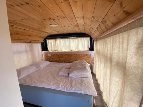a bed in a trailer with a wooden ceiling at The Bus in Majdal Shams