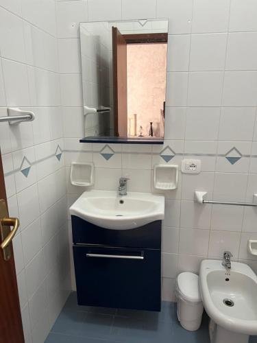 een badkamer met een wastafel, een toilet en een spiegel bij Perla in Cefalù