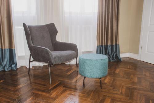 a chair and a stool in a room at Allegro apartments city center in Oradea