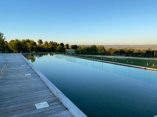 une grande étendue d'eau avec une promenade en bois dans l'établissement thecamp Hôtel & Lodges - Aix en Provence, à Aix-en-Provence