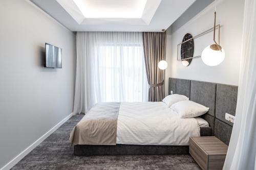 a bedroom with a large bed and a window at Hotel Caprice in Bacău