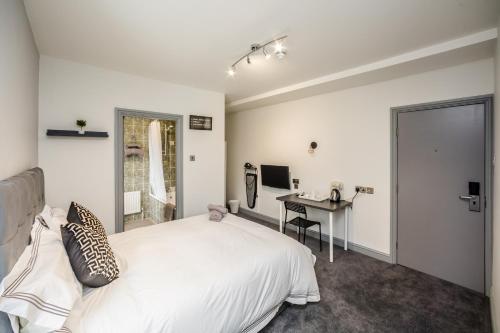 a bedroom with a white bed and a desk at Huddersfield Central Lodge in Huddersfield