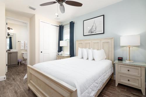um quarto com uma cama branca e uma ventoinha de tecto em Hakuna MaCottage em Orlando
