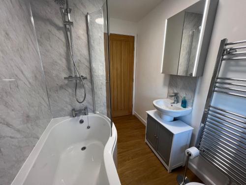 a bathroom with a white tub and a sink at Escapism Wales Garthowen in Llanrhystyd
