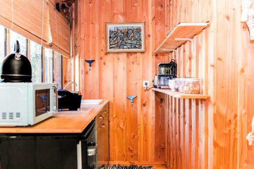 - une cuisine avec des murs en bois et un comptoir avec un four micro-ondes dans l'établissement Cabane MIMI, à Arès