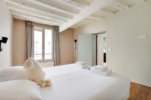 2 białe łóżka w pokoju z oknem w obiekcie Apt archetype parisien dans une rue emblématique ! w Paryżu