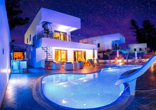 a villa with a swimming pool at night at Seafront Protaras Villas in Protaras