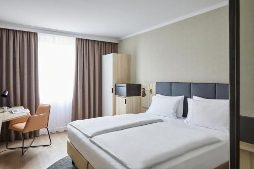 ein Hotelzimmer mit einem großen Bett und einem Schreibtisch in der Unterkunft Crowne Plaza Hamburg-City Alster, an IHG Hotel in Hamburg