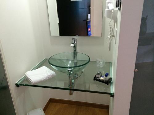 y baño con lavabo de cristal y espejo. en Benidorm Hotel, en Manizales