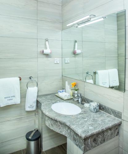 a bathroom with a sink and a mirror at Weston Hotel in Nairobi