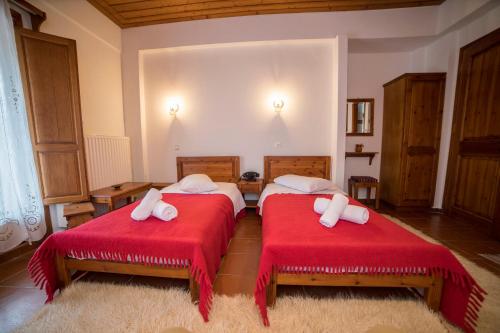 two beds in a room with red sheets and towels at Ξενώνας Πατρικό in Neraïdochóri